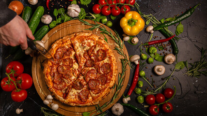 Tasty pepperoni pizza and cooking ingredients tomatoes basil on black concrete background. Top view of hot pepperoni pizza. With copy space for text. Flat lay. Banner