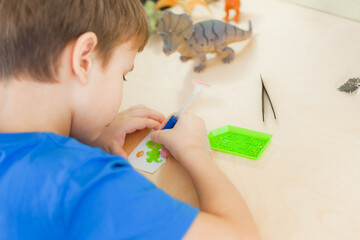 Close up of little boy creating a diamond mosaic, selective focus.