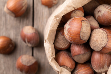 Hazelnuts in a paper bag over wooden table