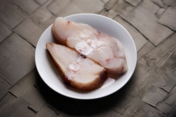 a pair of slices of raw monkfish in a white plate