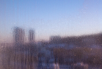 View of the city through icy glass. Winter pink sunset. Icy wind