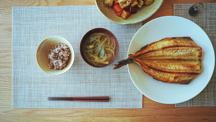 Japanese food with grilled fish, rice and miso soup on the table.
