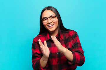 latin woman feeling happy and successful, smiling and clapping hands, saying congratulations with...