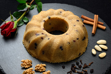Homemade semolina halva with raisins served on black dish with nuts and cinnamon