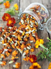 Folk medicine. Dried red flowers of marigold-marigolds on a wooden background in a glass jar for...