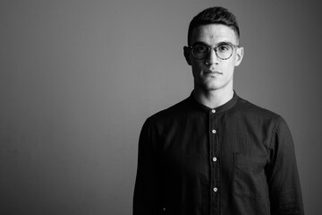 Young handsome businessman wearing eyeglasses against gray background