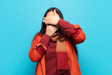 latin woman covering face with both hands saying no to the camera! refusing pictures or forbidding...