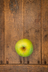 looking straight down on a green apple sitting on a antique farm table