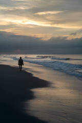 silhouette of a person walking on the beach at sunrise