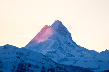 Naklejka premium peak of Schreckhorn at dawn with red clouds in winter
