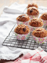 Freshly baked homemade cupcakes in coloured moulds on a cooling rack, on the table with kitchen cloths
