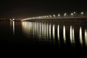 Obraz premium Reflection of bright lanterns in the Dnieper river under the bridge