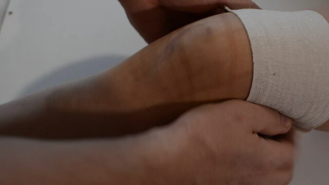 Trauma doctor provides first aid to an injured child's knee by applying a medical elastic bandage	
