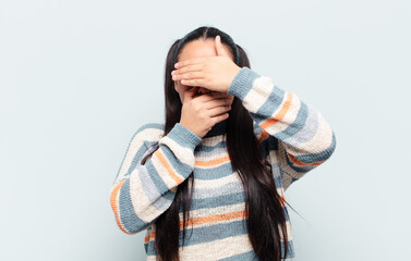 latin woman covering face with both hands saying no to the camera! refusing pictures or forbidding...
