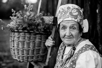 Portrait of old woman in ethnic clothes outdoor. Black and white photo.