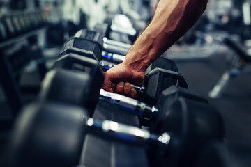 Rows of dumbbells in the gym with hand - obrazy, fototapety, plakaty
