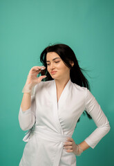 a beautician in a white suit and transparent gloves holds a medicine on a turquoise background with space for text