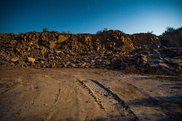 Fototapeta na wymiar Large deposits of stone materials near a mine in the Carpathians against the background of the sky with the moon