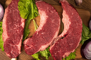 Raw marbled beef steaks with lettuce, red onion, garlic and cucumber