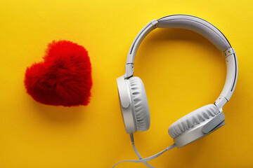 Red heart and white headphones on a yellow background. Love music lifestyle concept. Valentine's Day