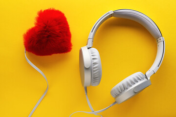 Red heart and white headphones on a yellow background. Love music lifestyle concept. Valentine's Day