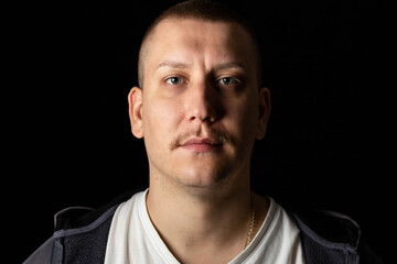 Close-up portrait of a strong, confident male person. Dark, black background