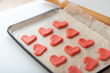 Fototapeta na wymiar Shortcrust pastry with red dye for making cookies for Valentine's Day in the form of red hearts.
