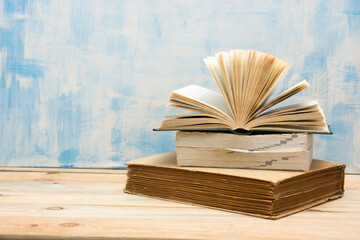 Composition with vintage old hardback books, diary, fanned pages on wooden deck table and red background. Books stacking. Back to school. Copy Space. Education background.