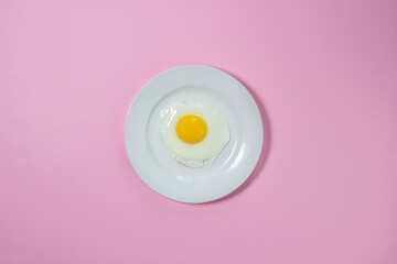 Scrambled eggs on a pink background. Fried eggs on a white plate. Tasty breakfast.