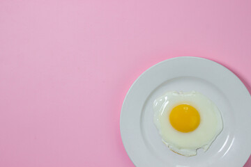 Scrambled eggs on a pink background. Fried eggs on a white plate. Tasty breakfast.