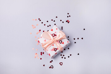 Gift Box with Bow on Light Blue Background Red Confetti Top View Horizontal Holiday Concept or Background Valentine Day