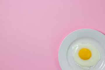 Scrambled eggs on a pink background. Fried eggs on a white plate. Tasty breakfast.