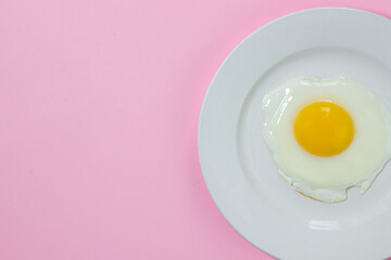 Scrambled eggs on a pink background. Fried eggs on a white plate. Tasty breakfast.