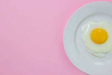Scrambled eggs on a pink background. Fried eggs on a white plate. Tasty breakfast.