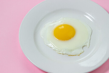 Scrambled eggs on a pink background. Fried eggs on a white plate. Tasty breakfast.