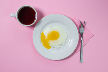 Scrambled eggs on a pink background. Fried eggs on a white plate. Delicious breakfast with a cup of coffee.