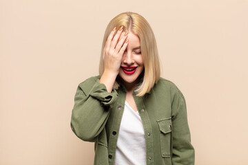 blonde woman laughing and slapping forehead like saying d’oh! I forgot or that was a stupid...