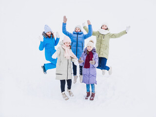 Joyful girls are jumping hand in hand in winter on a walk. Fashionable winter clothes