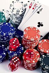 Studio photo of poker game set, card deck, red dice and poker chips in variated colors. Selective focus on object.