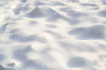 Snow texture on a clear, sunny day. Natural background. Small bumps of snow. Copy space, place for text.