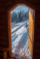 View from  wooden house with plunge font pool for ablutions at the holy spring in a natural park in sunny winter day.