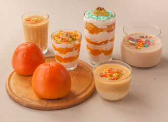 Desserts of persimmon and yoghurt, soufflé and persimmon fruits on a wooden board