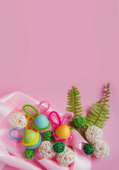 Happy Easter. Easter campaign of colorful eggs with bunny ears, leaves, ornaments and ribbons on a pink background. Vertical banner. View from above. Easter card. Horizontal format, banner. Copyspace