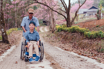 Disabled child on wheelchair is playing, learning and exercise in the outdoor like other people with parent,Forest background,Lifestyle of special child in education age, Happy disability kid concept.