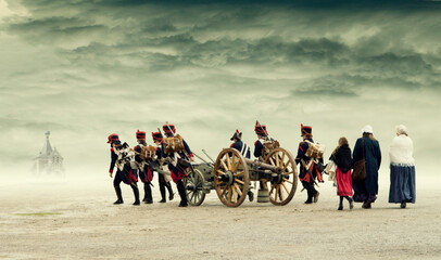 Napoleonic soldiers and women marching and pulling a cannon through plain land, countryside with stormy clouds. Soldiers going towards a russian orthodox church on horizon. No recognizable persons.