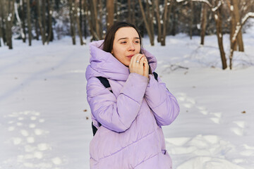 an emotional female in a purple down jacket enjoys the snow in the park