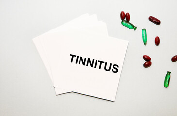 on the sheets for notes text TINNITUS, next to red and green capsules.