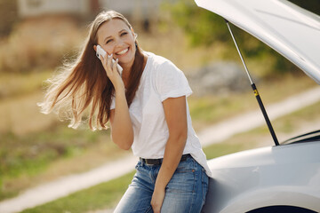 Woman by the car. Lady in a white t-shirt. Woman with mobile phone.