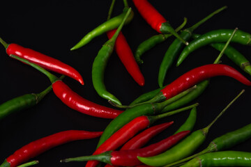 Red and green chili peppers on black background.