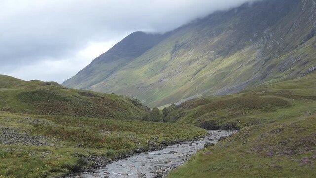 A tilt shot of Scottish highlands and a water stream.